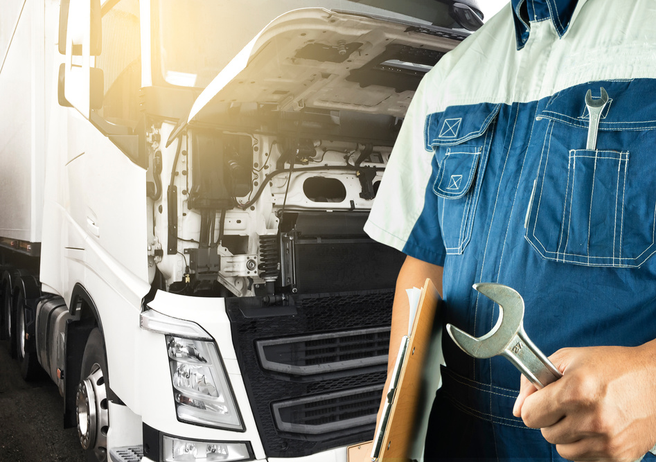 Professional auto technician holding wrench and repairing a semi truck a